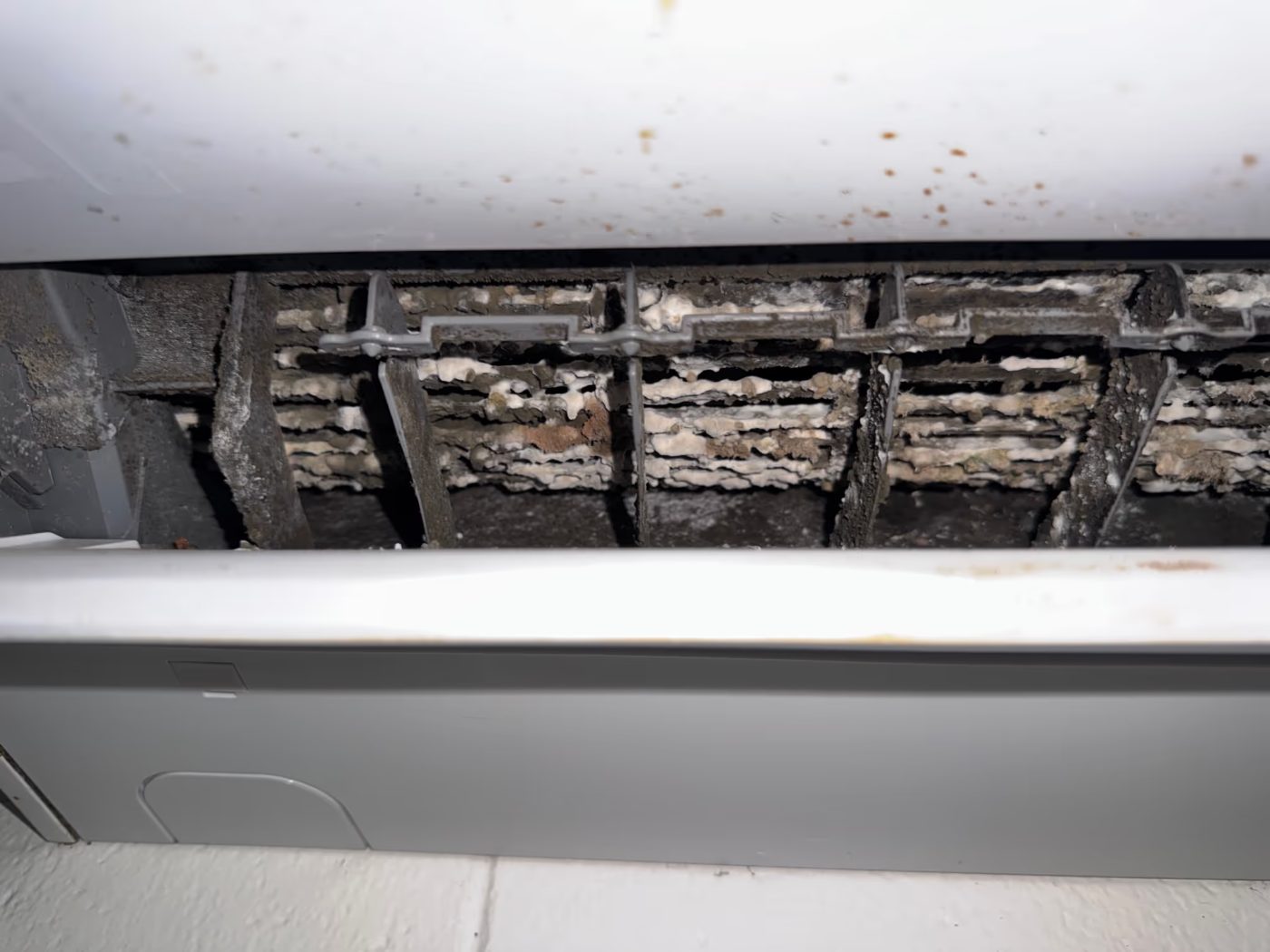 Close-up of an air conditioner heat exchanger caked in grime and mould before cleaning